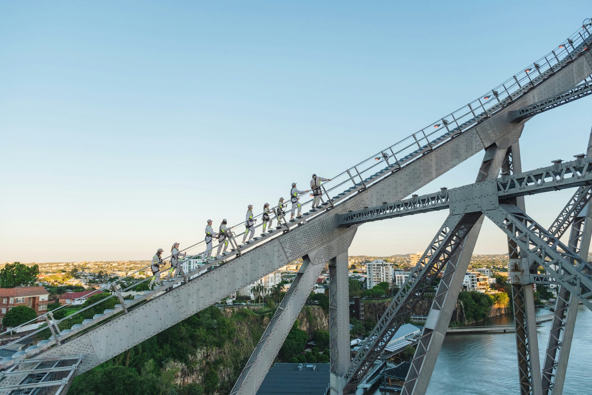 People climbing a bridge high above the city