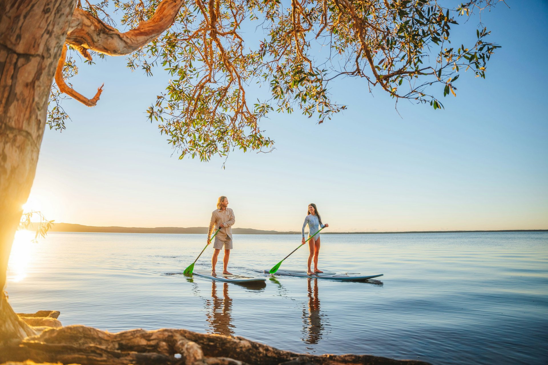 Paddleboarders in calm water at sunset
