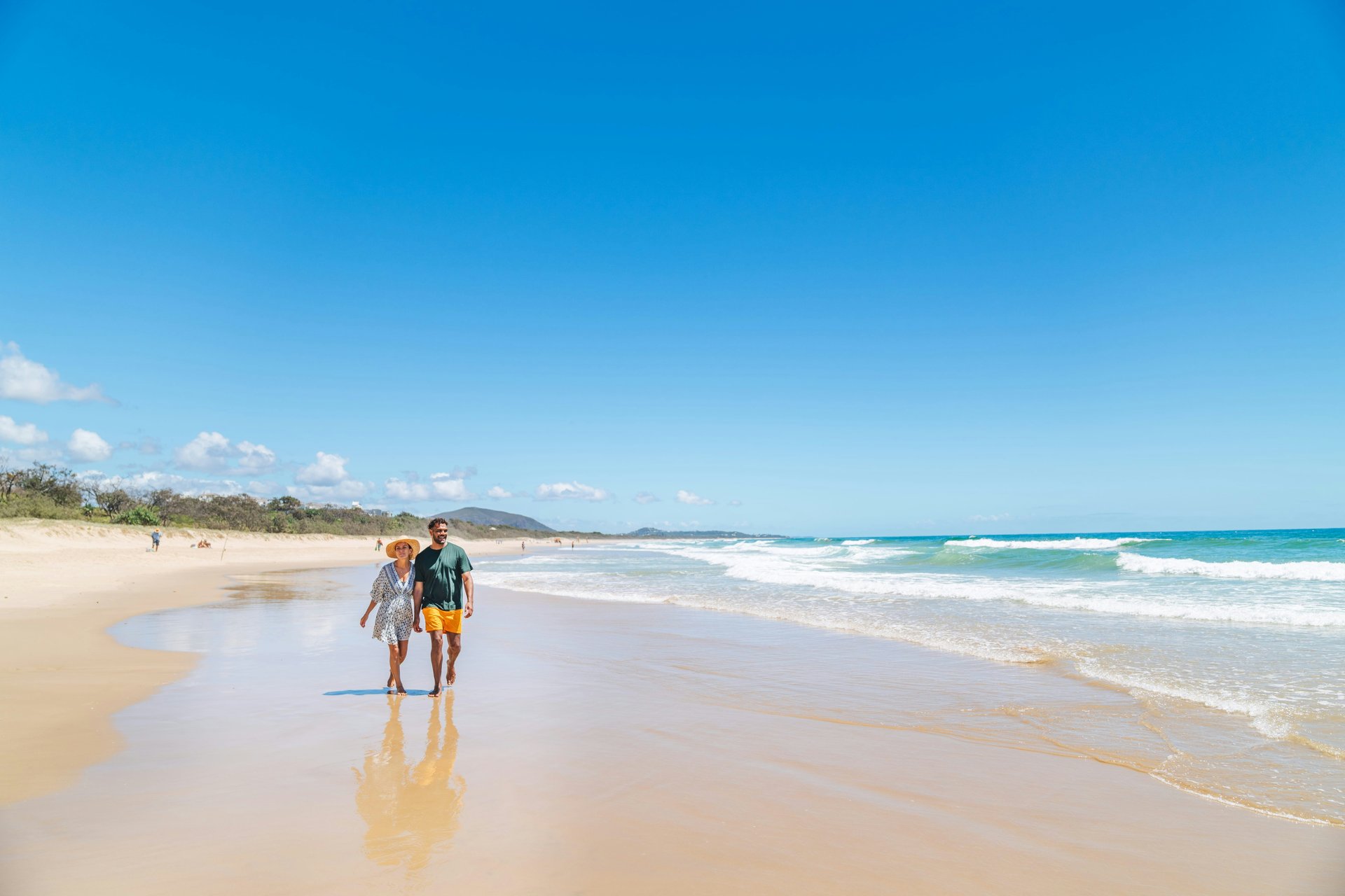 Travellers walking along a wide sandy beach