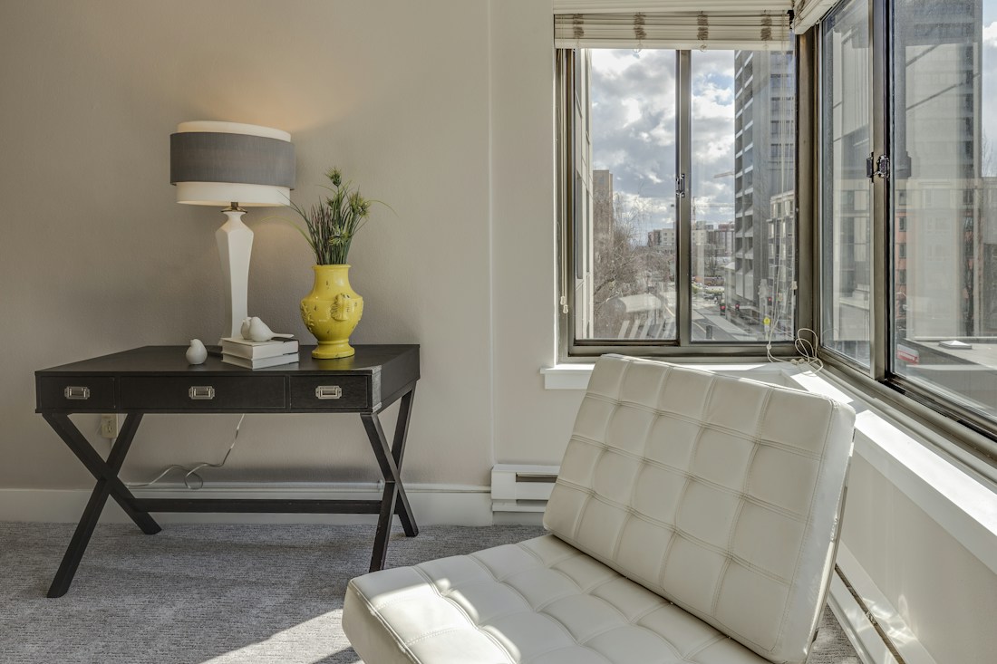 Cream lounge chair and lamp beside a window and warm neutral wall